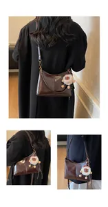 Detail of glossy dark brown tote bag with a cute lion plush pendant and smooth finish