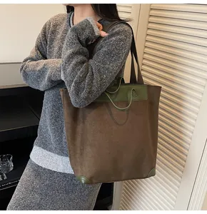 Detailed view of large corduroy tote bag with green leather trim and shoulder strap