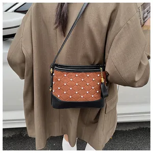Détail du sac seau matelassé en daim marron avec pampille et bandoulière élégante