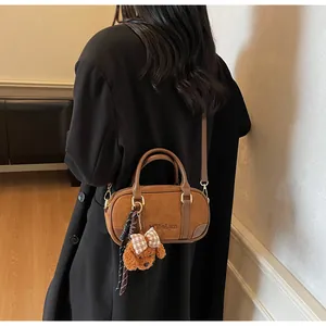 Detail of vintage brown suede bowling bag with puppy charm and checkered bow accessory
