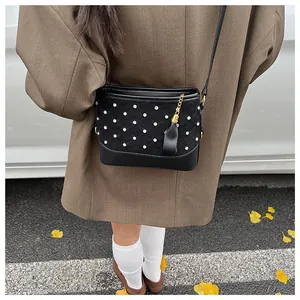 Détail du sac seau noir avec grille de strass et breloque à pompon doré élégant