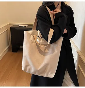 Detail of cream corduroy tote bag with white leather trim and brown woven shoulder strap