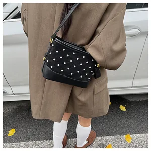 Detail of black frosted bucket bag with quilted patterns and pearl studs on leather
