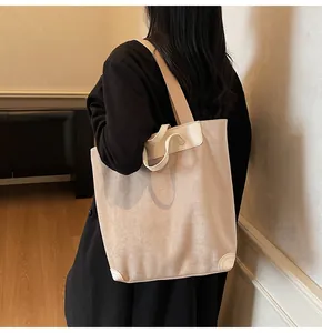 Detail of minimalist corduroy tote bag showing reinforced leather corners and wide strap