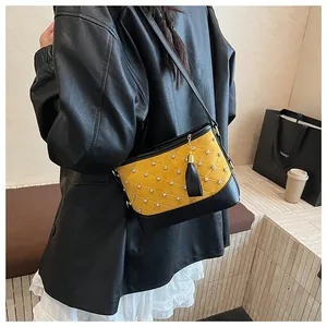 Vue détaillée du sac seau jaune matelassé avec strass et pompon noir en cuir élégant
