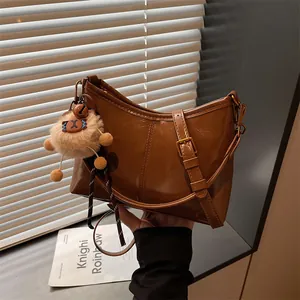 Caramel brown glossy faux leather tote bag with plush charm and adjustable strap