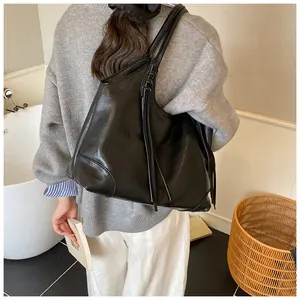 Vue détaillée du grand sac cabas noir avec pompon porté par un mannequin de dos