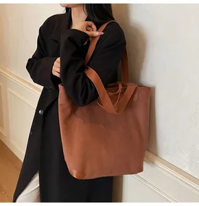 Detail view of large brown corduroy tote bag showing leather reinforced bottom corners