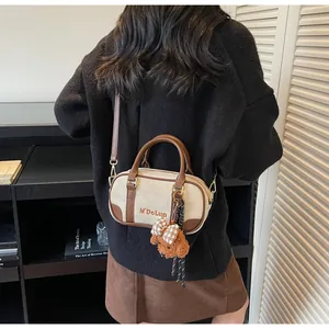 Detail of Boston bag showing white fabric, brown leather trim and cute teddy bear charm