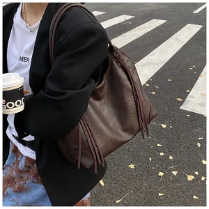 Détail du sac cabas en cuir marron foncé avec longues franges et bandoulière tressée