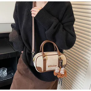 Detail of cream canvas and brown leather bowling bag with cute puppy bag charm accessory