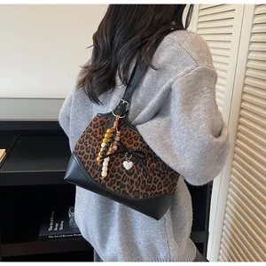 Leopard print crossbody bag detail with black bow and heart charm on a model