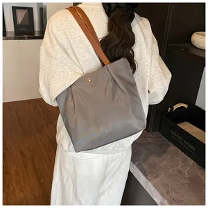 Detail of grey tote bag with brown straps and magnetic snap closure on model