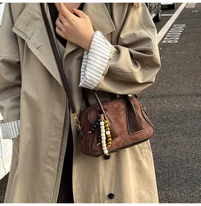 Close-up of brown suede crossbody bag with decorative wooden beads and leather strap