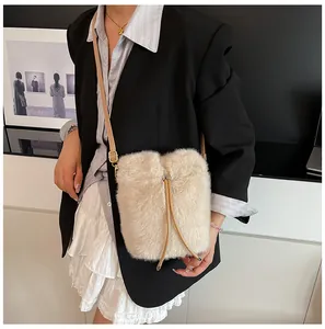Detailed macro shot of the cream faux fur texture and drawstring on the bucket bag
