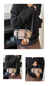 Detail of khaki Boston bag with M'DoLun logo, black leather trim and cute bear charm