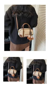 Detail of off-white canvas bowling bag with brown leather trim and a cute teddy bear charm