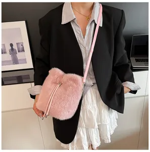 Close-up of a pink plush bucket bag with silver chain worn by a model in autumn style