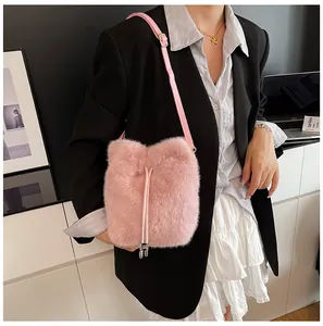 Detailed view of pink plush bucket bag with chain strap styled with black blazer outfit