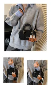 Detail of a black bowling bag featuring a plush bear charm and textured material finish