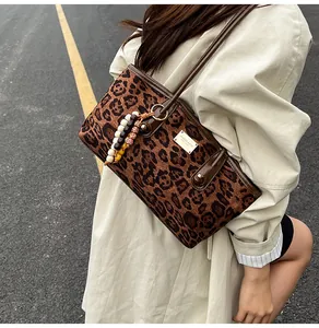 Detail of leopard print crossbody bag featuring silver logo and colorful beaded tassel charm