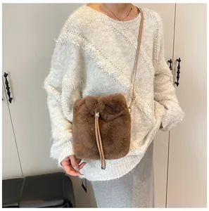 Detail of plush bucket bag with golden hardware and leather strap on white sweater
