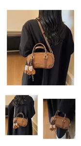 Detail of brown suede bowling bag featuring leather handles and a cute dog charm