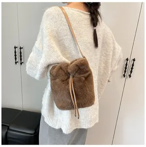Detail of plush bucket bag with drawstring closure and brown leather strap on model