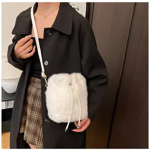 Detail shot of a white faux fur bucket bag with drawstring closure and golden hardware