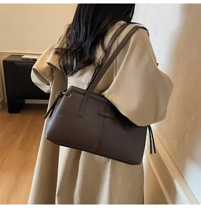Detail view of a dark brown leather shoulder bag with ZHENMA logo and drawstring sides