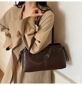 Detail of a dark brown vintage shoulder bag with drawstring accents and a slim strap