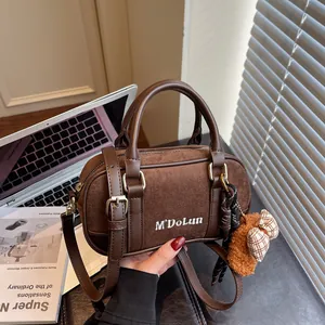 Brown bowling shoulder bag with plush bow charm and vintage aesthetic design