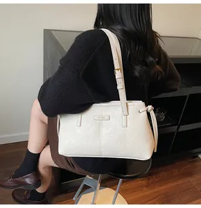Model wearing a minimalist cream leather shoulder bag with gold hardware for a chic look