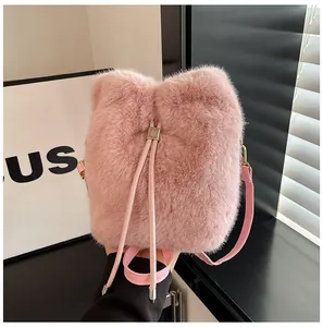 Detailed view of pink plush bucket bag featuring a gold metal charm engraved with Fu character
