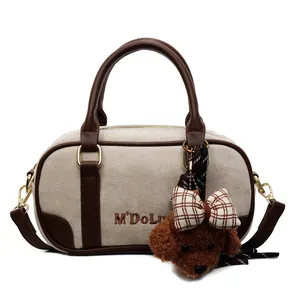 Beige Boston bowling bag with brown trim and cute plush bear charm on white background