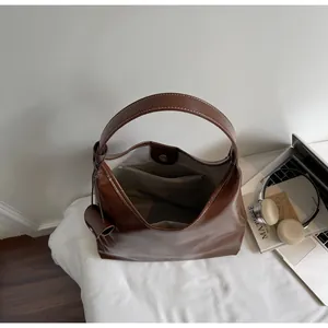 Brown faux leather tote bag with contrast stitching, laptop, and accessories on white desk
