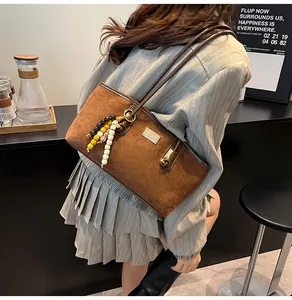 Detail of vintage brown suede shoulder bag with beaded fringe and metallic logo plate