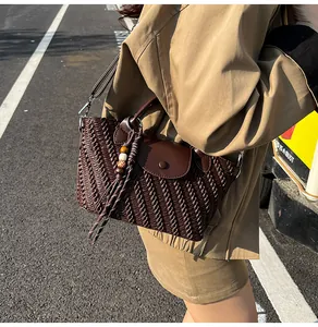 Detail einer dunkelbraunen geflochtenen Tasche mit Holzperlenquaste und silbernen Schnallen
