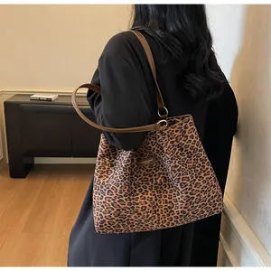 Détail du cabas en toile léopard avec anses en cuir marron et étiquette logo