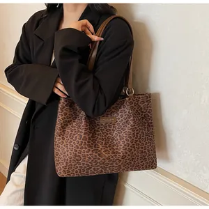 Détail du sac cabas en toile léopard avec bandoulières marron et écusson de marque