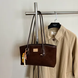 Brown suede underarm shoulder bag with colorful beads on a beige trench coat