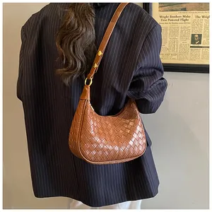Detail of woven crescent shoulder bag in dark brown with gold metal adjustment studs