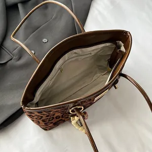 Leopard print tote bag with brown leather handles and a beaded keychain accent