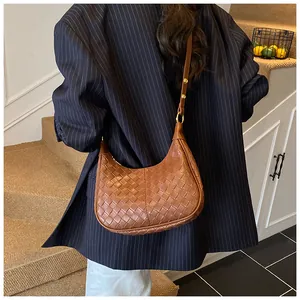 Detail of deep caramel woven leather hobo bag with gold buckle on shoulder strap