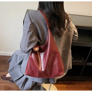 Close-up of wine red glossy leather tote bag showing golden logo and refined texture