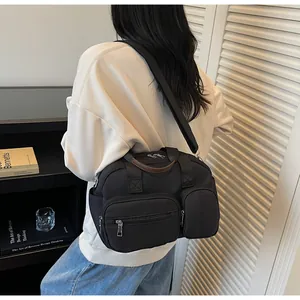Vue portée d'un sac bandoulière noir en nylon multi-poches avec large sangle réglable