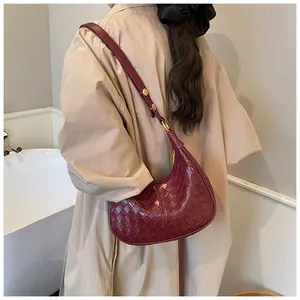 Macro shot of dark red woven leather texture and crescent shape on minimalist hobo bag