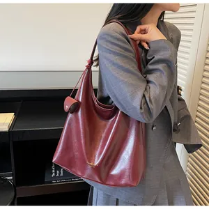 Detailed side view of a dark red leather tote bag with a small matching hanging coin purse