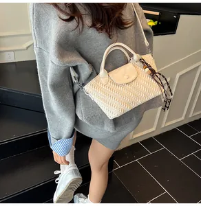 Detail der cremefarbenen geflochtenen Ledertasche mit lila Quaste und Schultergurt