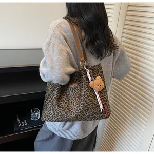 Détail d'un sac cabas léopard en toile avec bandoulière en cuir et breloque petit ours